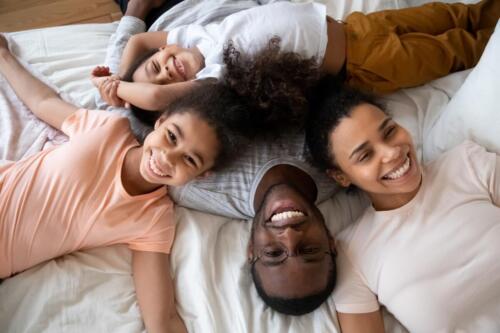 Happy,African,American,Parents,With,Little,Children,Lying,On,Bed
